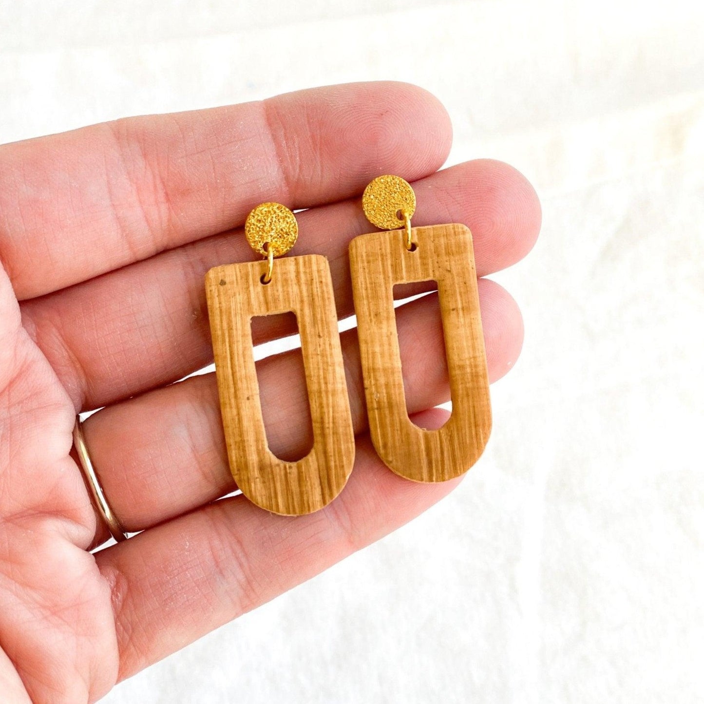 cute handmade brown earrings with gold surgical steel posts laying in human hand