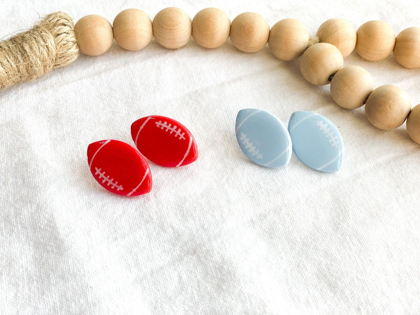 close up of NC State and UNC Handmade Football Stud Earrings with Surgical Steel Posts on white cloth