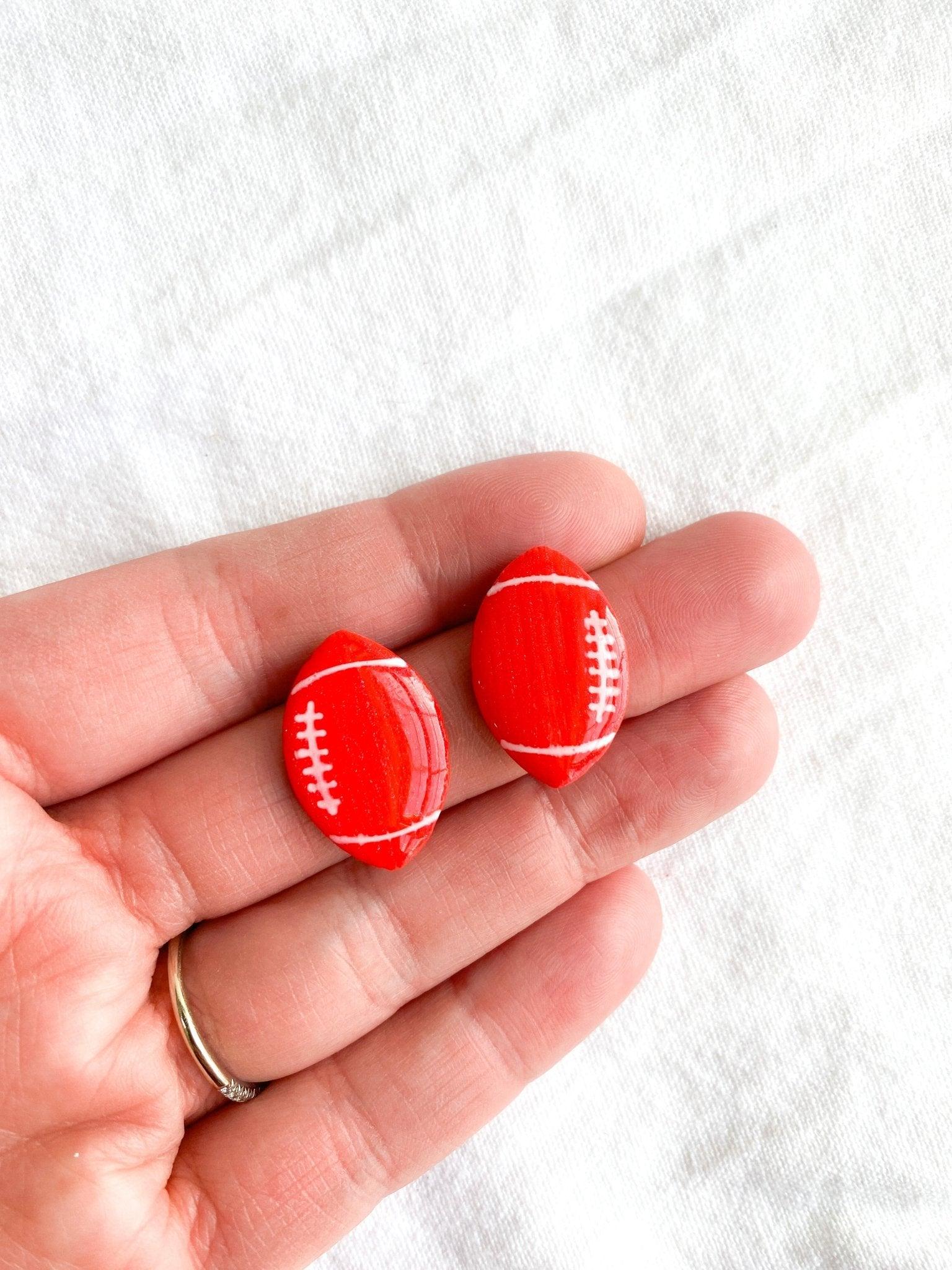 Bright Red NC State Wolfpack Handmade Football Stud Earrings with Surgical Steel posts in human hand