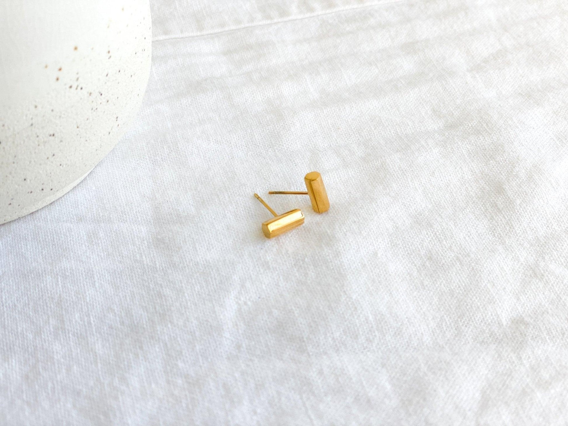 Small Gold Stud Bar Earrings with Surgical Steel Posts on White Linen Cloth