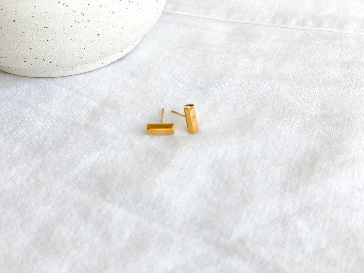 Small Gold Stud Bar Earrings with Surgical Steel Posts on White Linen Cloth