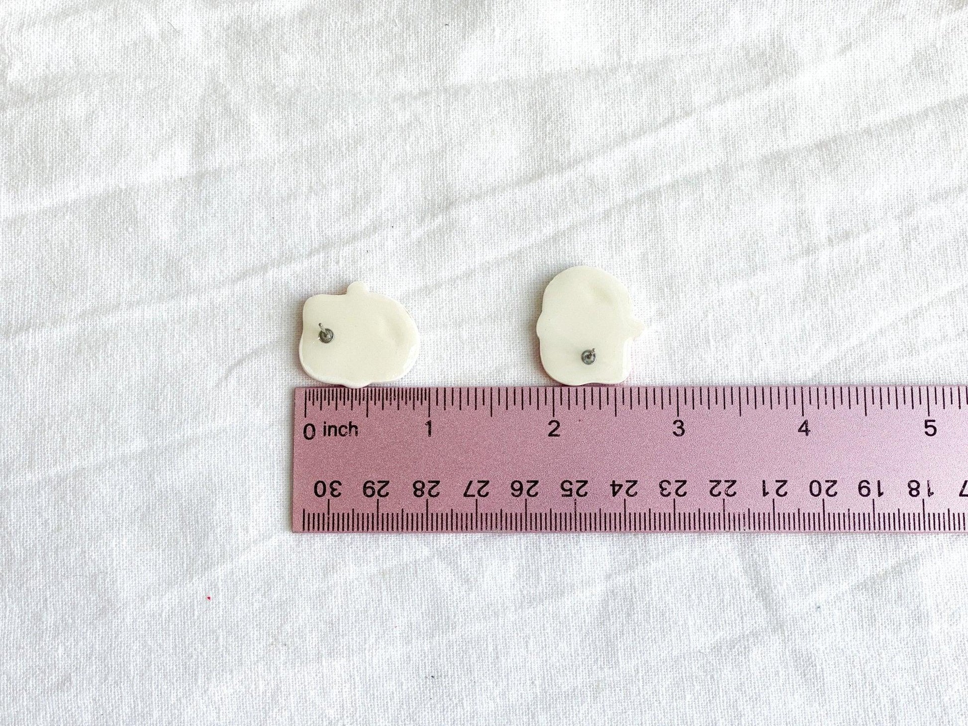 Handmade Jack Skellington with Santa Claus Hat Studs Upside Down Next To Pink Ruler On White Linen Cloth