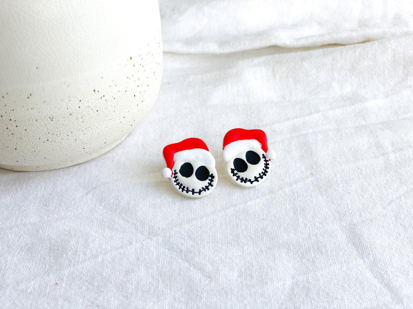 Handmade Jack Skellington with Santa Claus Hat Studs On White Cloth Next To White Ceramic Vase