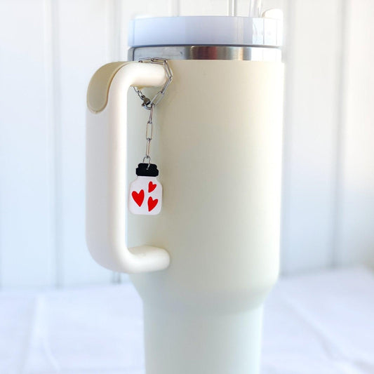 Handmade Love Potion Charm attached to Stainless Steel Paper Clip Chain on Handle of Cream Colored Stanley Cup