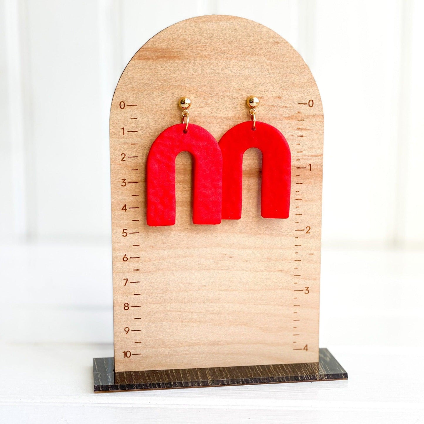 Textured Handmade Bright Red Earrings with Gold Surgical Steel Ball Posts Laying Flat on Wood Earring Measurement Stand