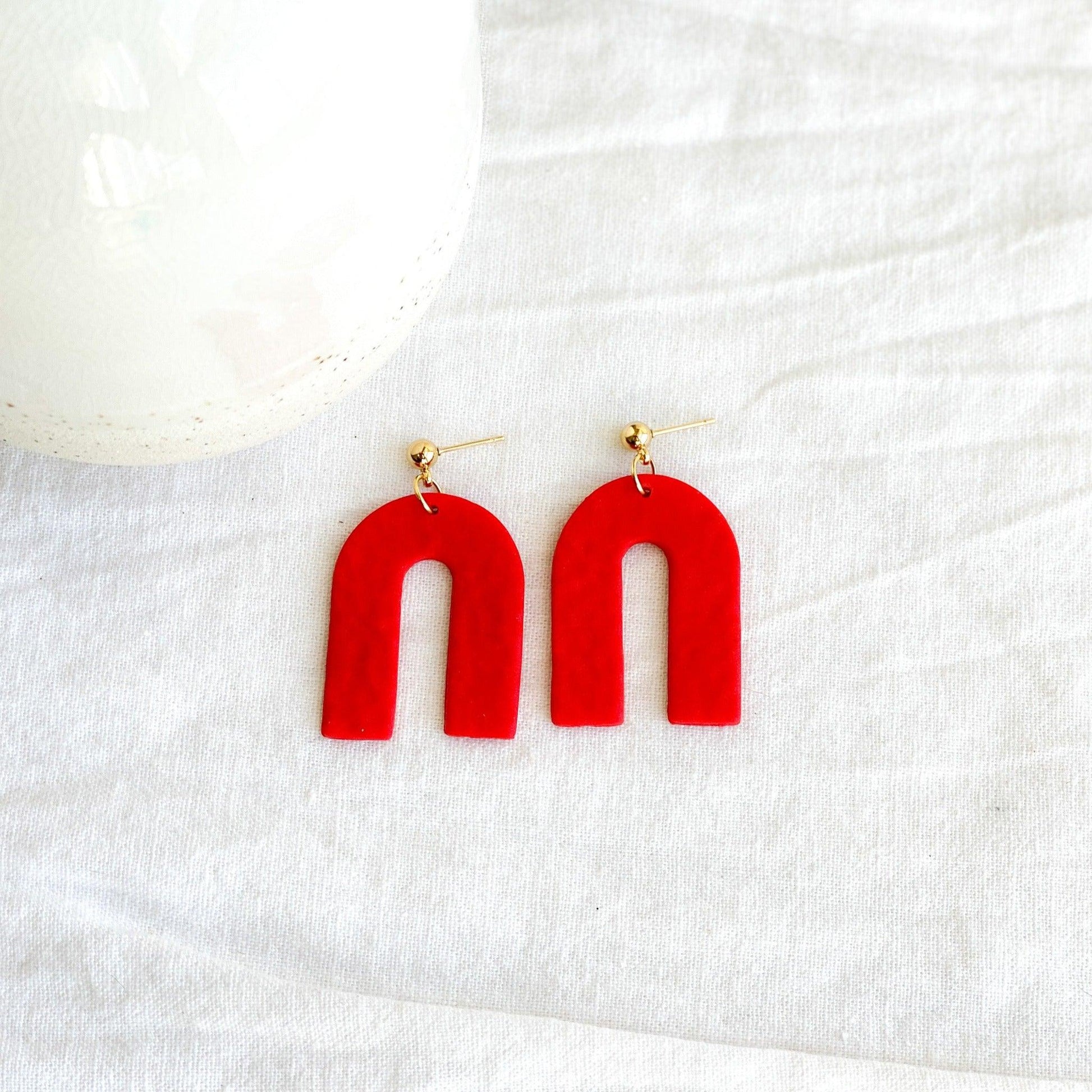 Textured Handmade Bright Red Earrings with Gold Surgical Steel Ball Posts Laying Flat on White Linen Cloth