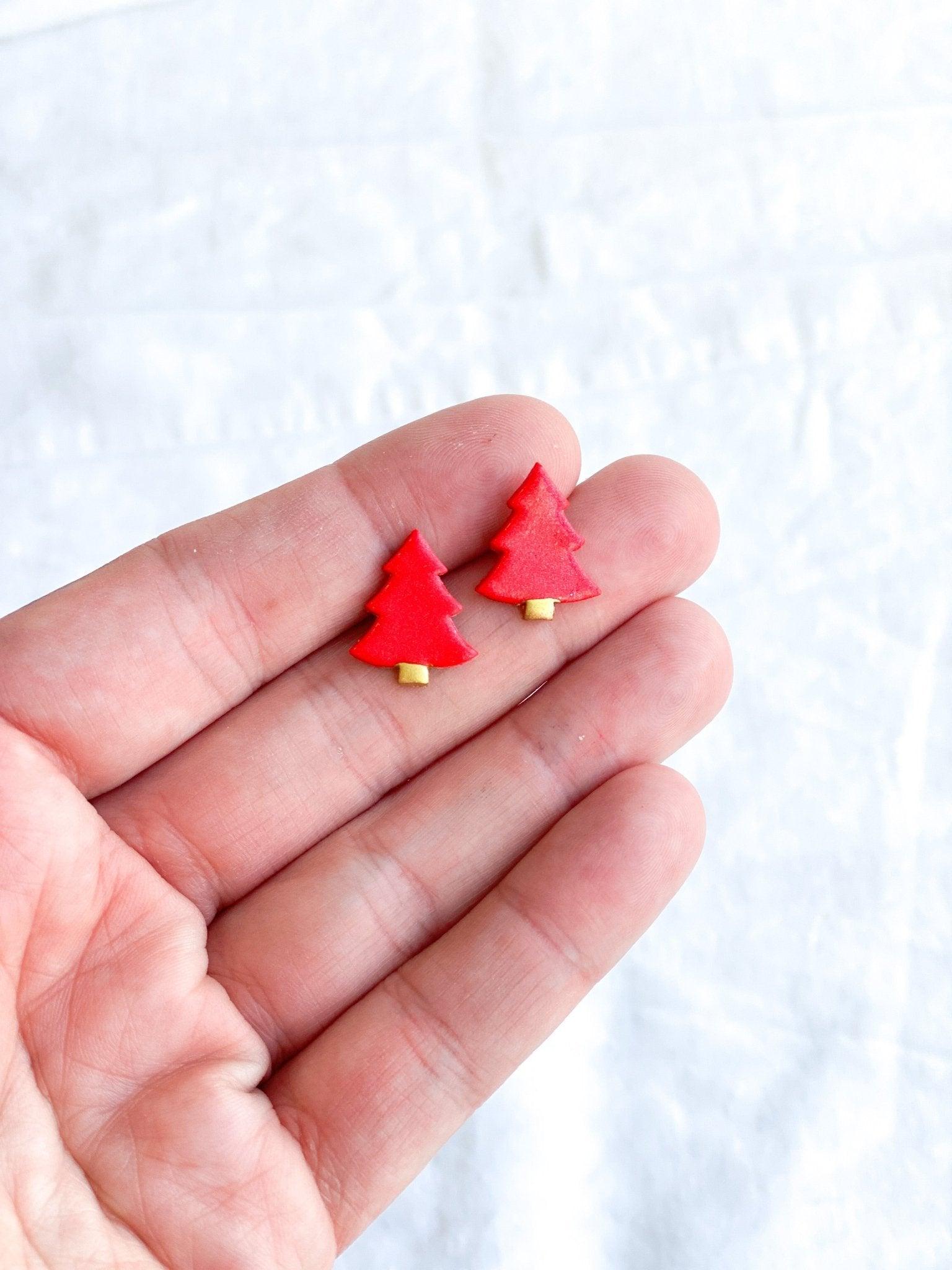 Red Stud Earrngs shaped like Christmas Trees with surgical steel posts held by human hand