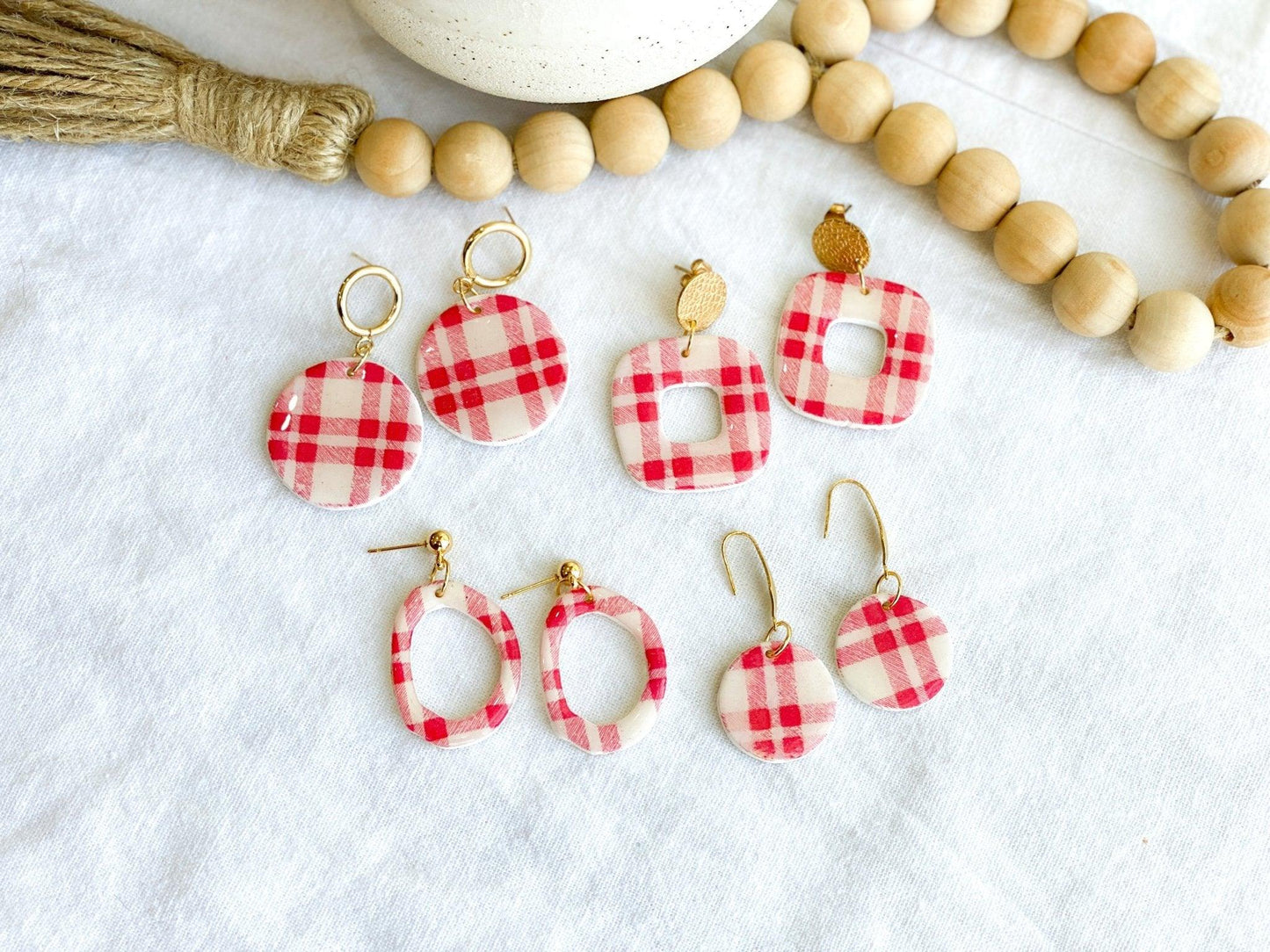 Multiple Pairs of Handmade Red Plaid Earrings with Gold Surgical Steel Posts laying on White Linen Cloth