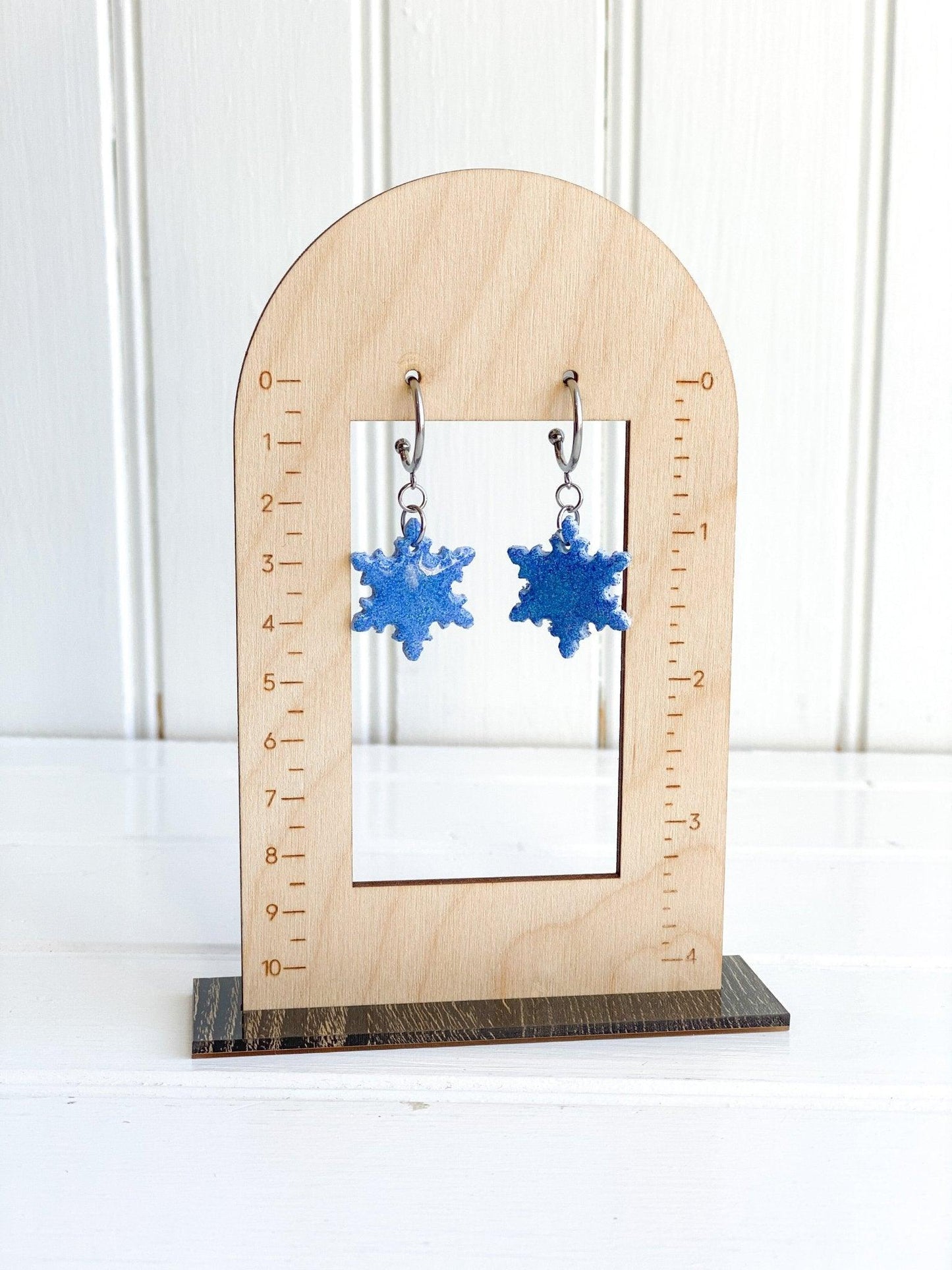 Handmade Sparkly Blue Snowflake Earrings on Silver Surgical Steel Huggie Earrings on Wood Earring Measurement Stand