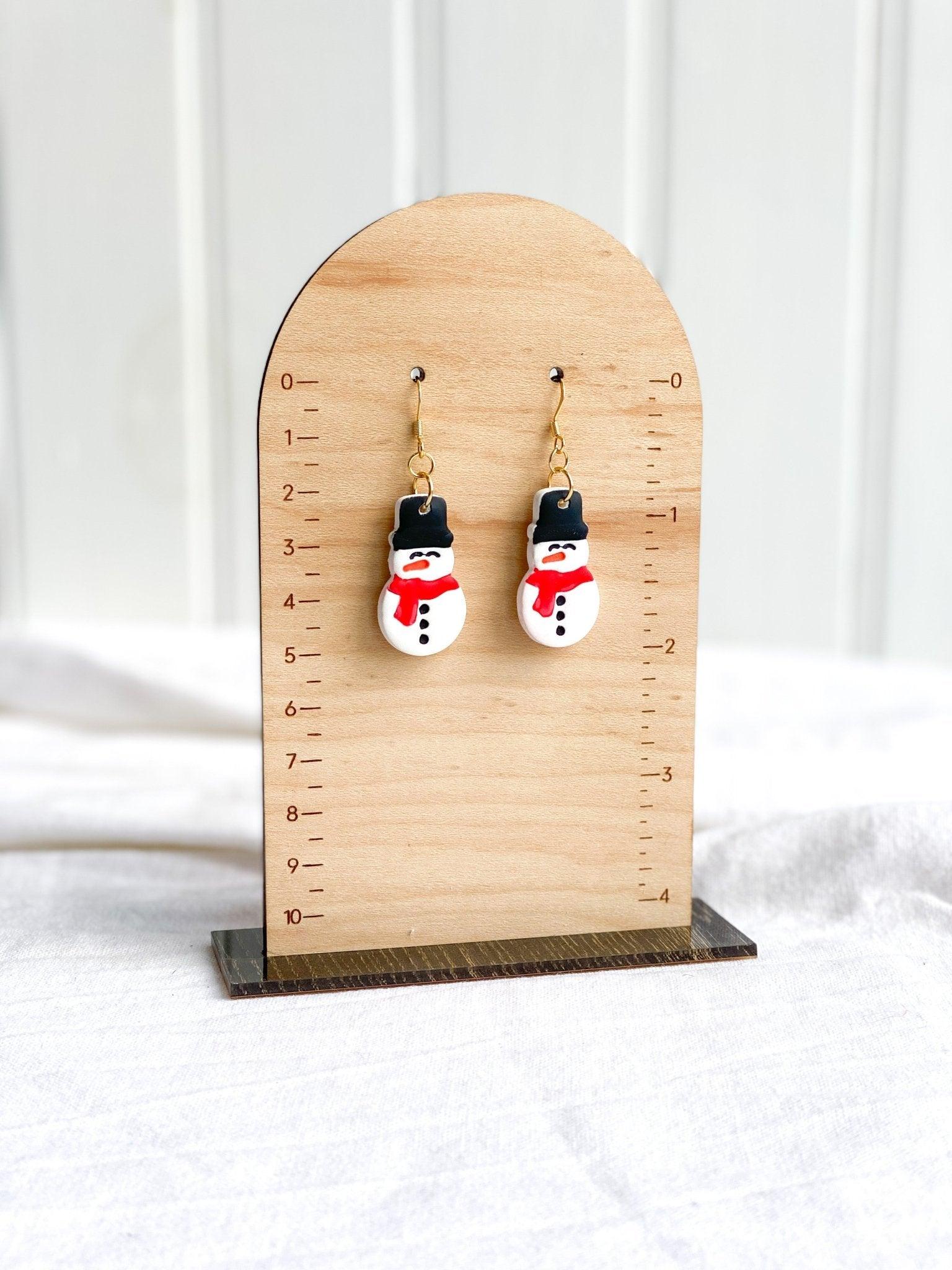 Cute Handmade Clay Snowman Earrings on Gold Ear Wires made from Surgical Steel on wood earring measurement stand