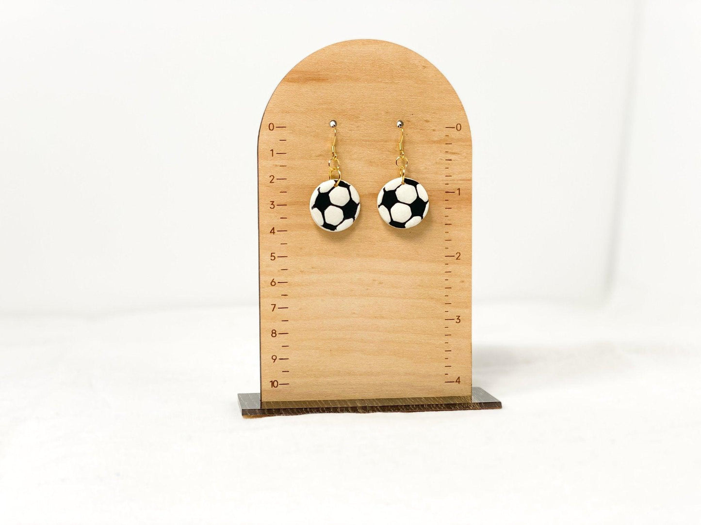 Handmade Soccer Earrings with Gold Surgical Steel Ear Wires on Wooden Earring Measurement Stand