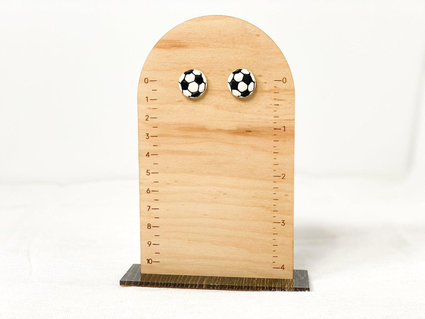 Small, Handmade Soccer Stud Earrings with Surgical Steel Posts on Wooden Earring Measurement Stand