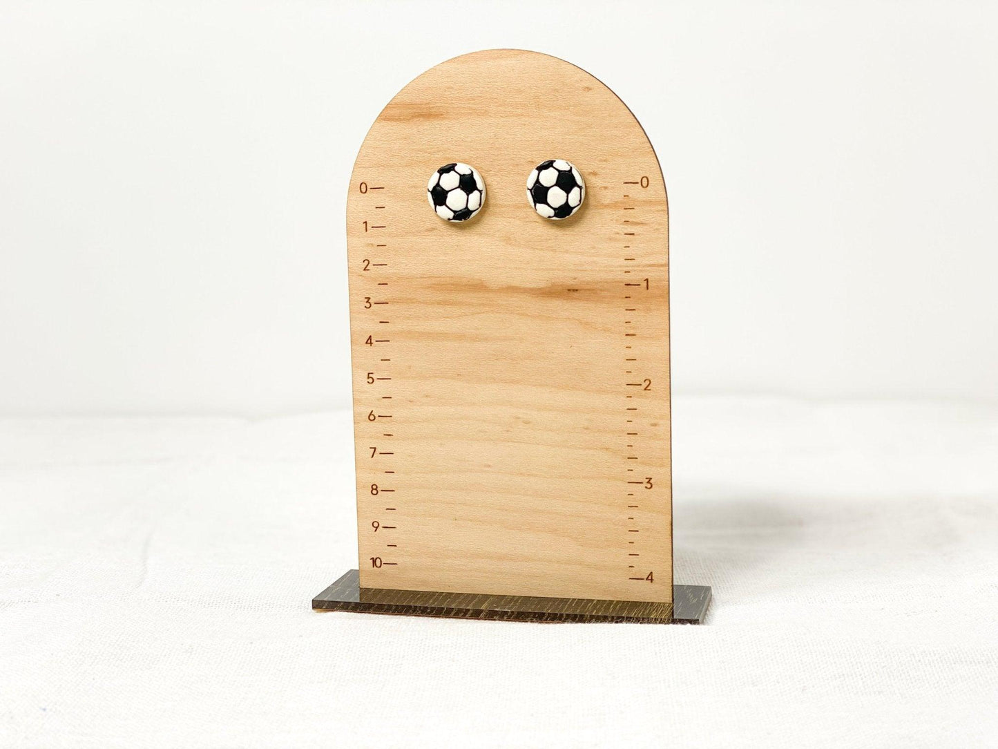 Small, Handmade Soccer Stud Earrings with Surgical Steel Posts on Wooden Earring Measurement Stand