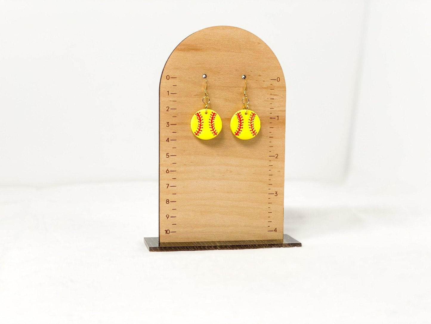 Handmade Softball Earrings with Gold Surgical Steel Ear Wires on Wood Earring Measurement Stand