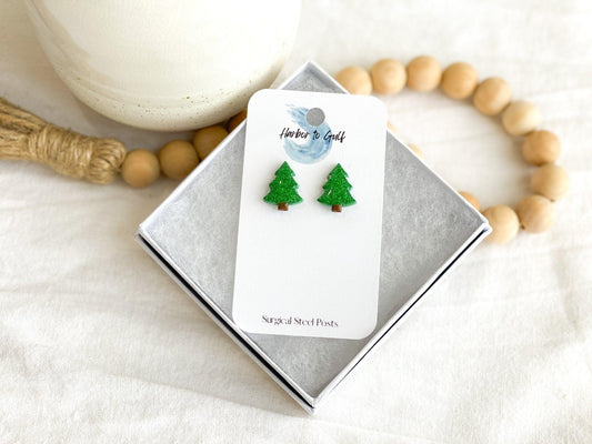 Small Handmade Green Sparkly Christmas Tree Stud Earrings on White Earring Card in White Gift Box propped on wooden beads