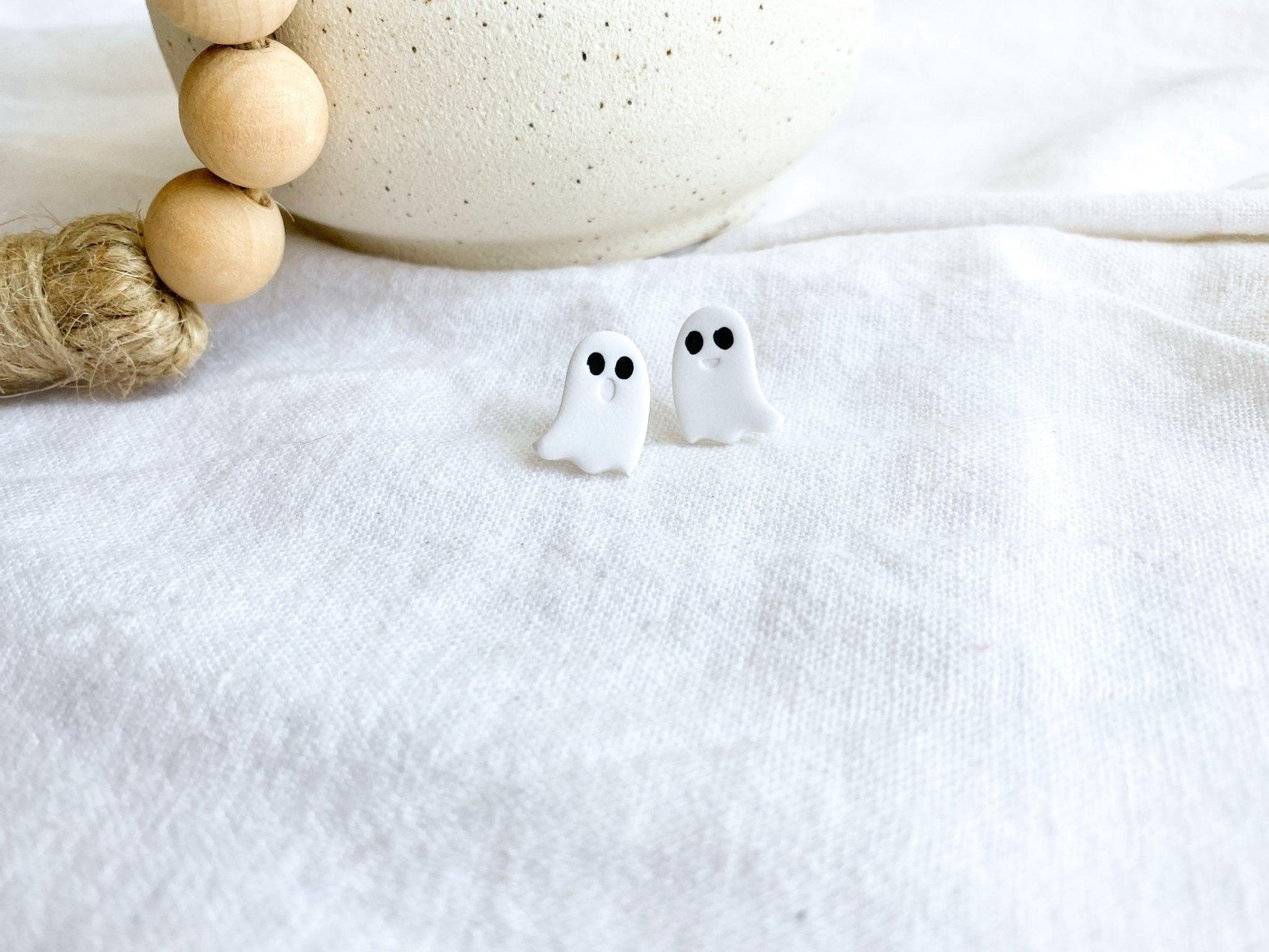 Small Handmade White Ghost Stud Earrings with Surgical Steel Posts on White Linen Cloth