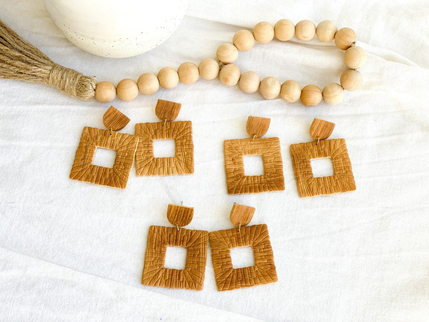 Three Pairs of Handmade Square Rattan Earrings attached to Rattan Stud Tops with Surgical Steel Posts laying on white cloth