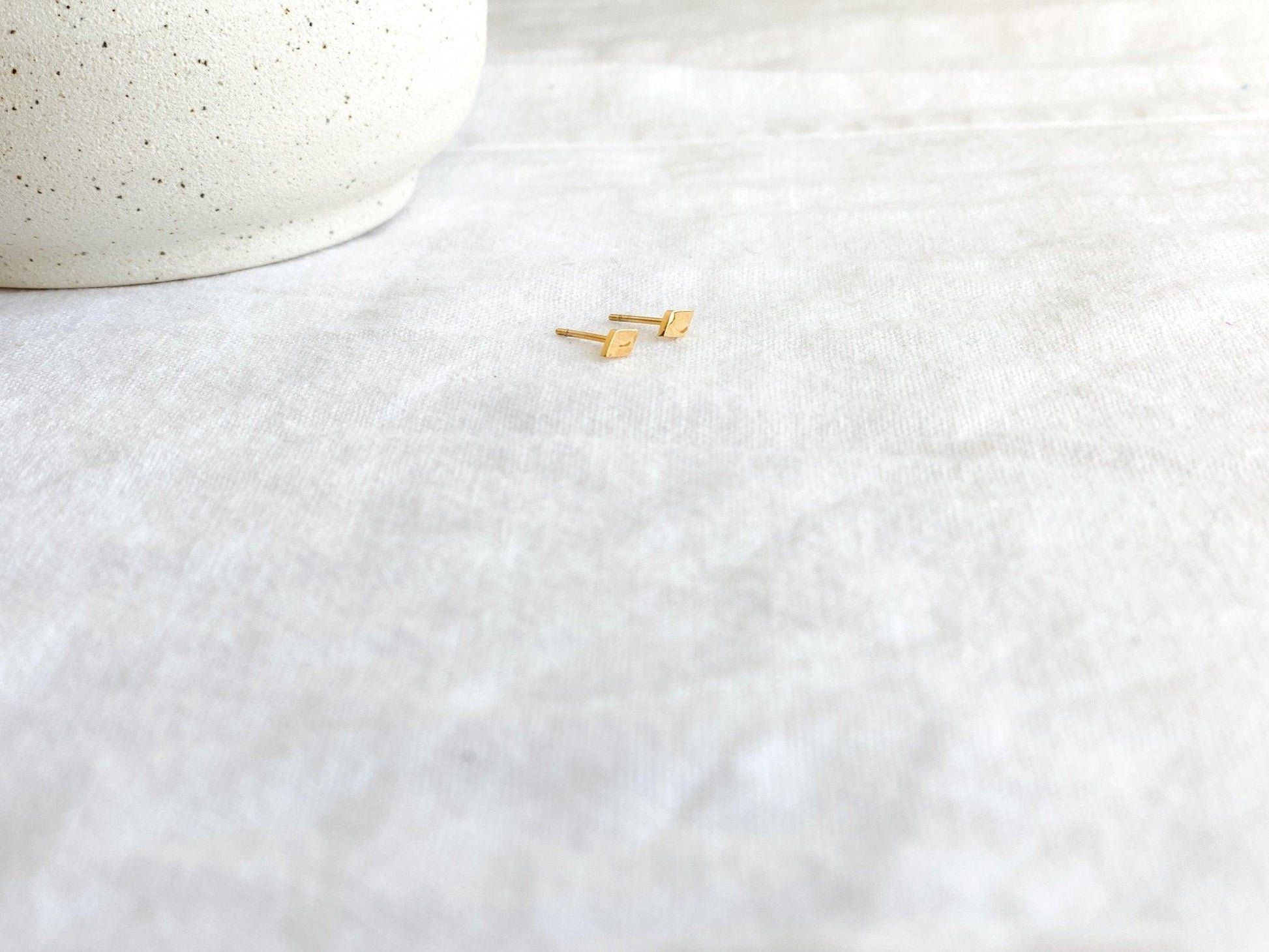 Tiny Gold Diamond Shaped Stud Earrings with Surgical Steel Posts on Earring Card on White Linen Cloth