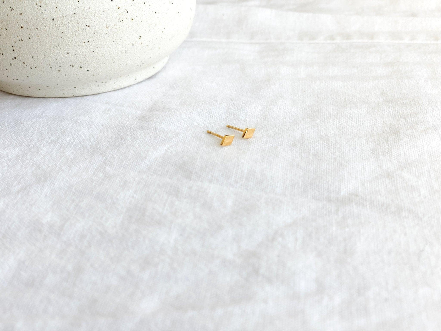 Tiny Gold Diamond Shaped Stud Earrings with Surgical Steel Posts on Earring Card on White Linen Cloth