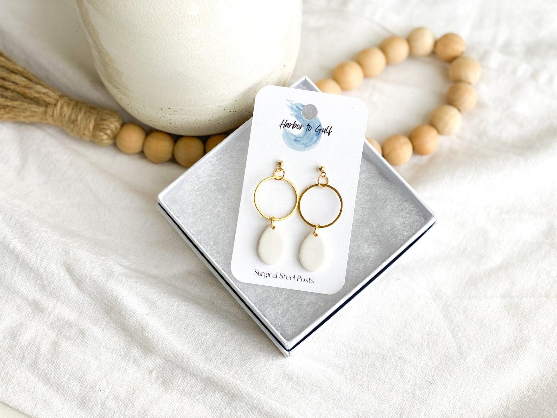 handmade white tear drops attached to thin open gold circles on gold ball posts displayed on earring card in white gift box